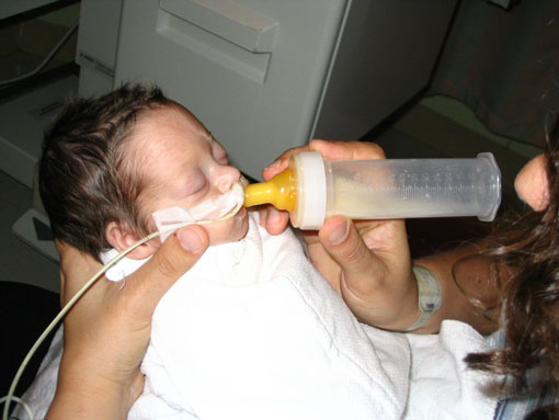 The technique for feeding a preemie is to squeeze the cheeks, support the chin and hold the baby and the bottle at the same time.  This was my first attempt... it took much more practice by both of us.